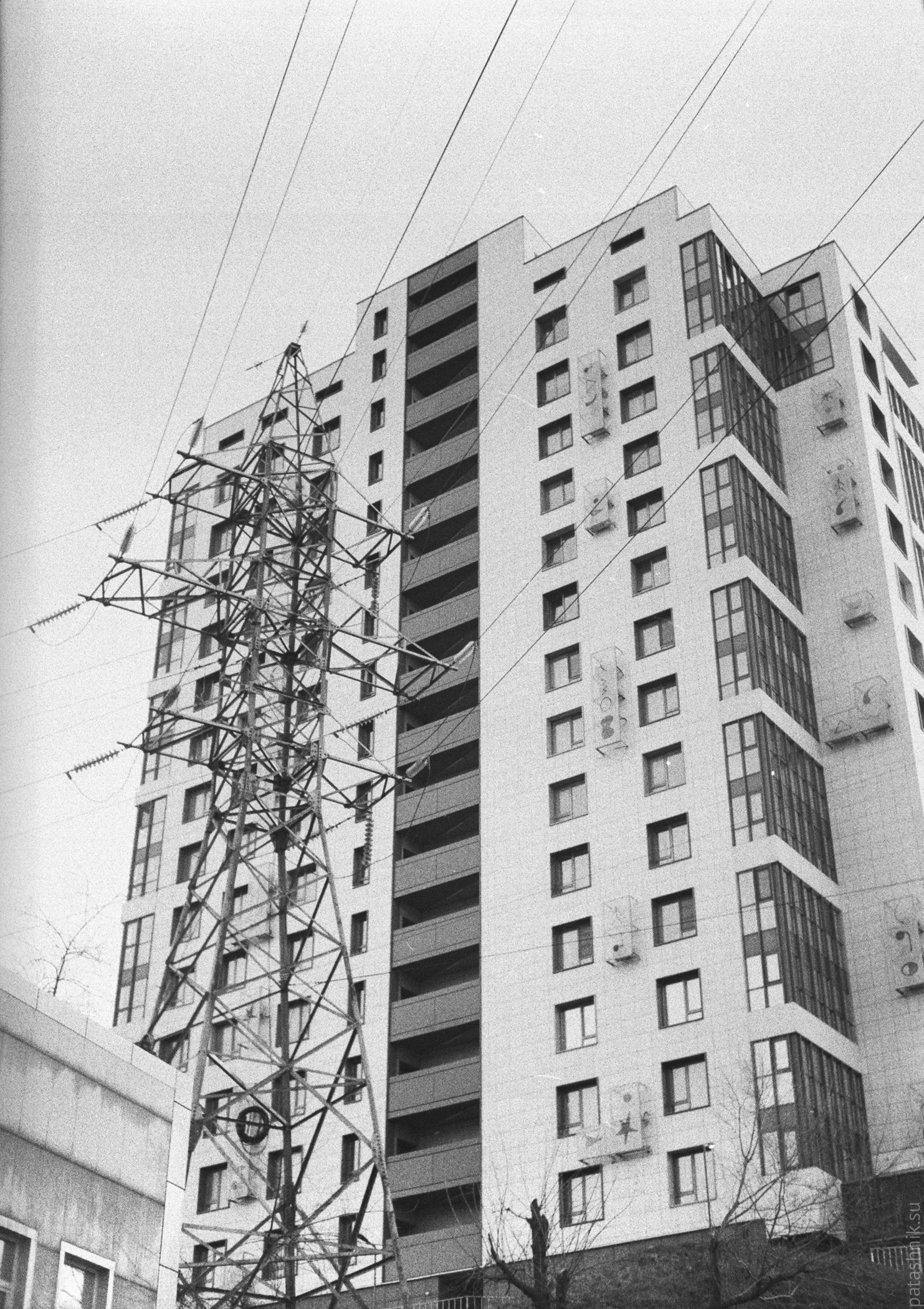 Transmission tower with modern apartment building on background